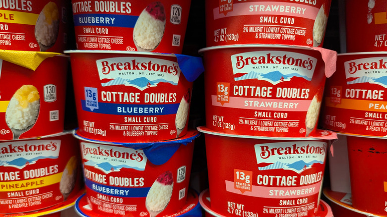 Various flavors of cottage cheese stacked on grocery store shelf