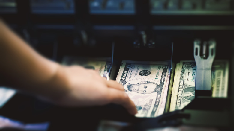 Hand taking money from cash register