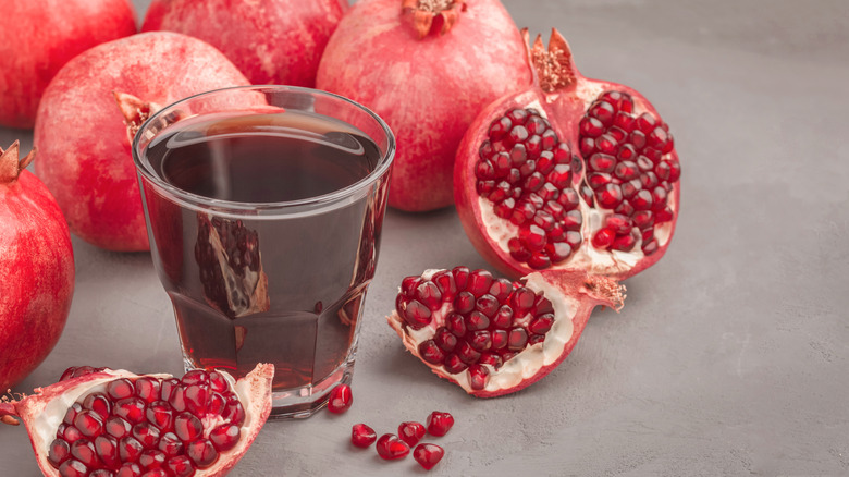 Pomegranate juice in glass surrounded by pomegranate