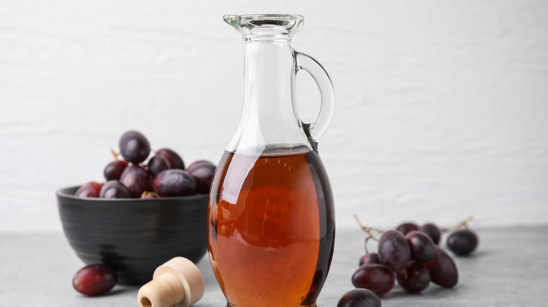 Red wine vinegar in bottle with grapes in background