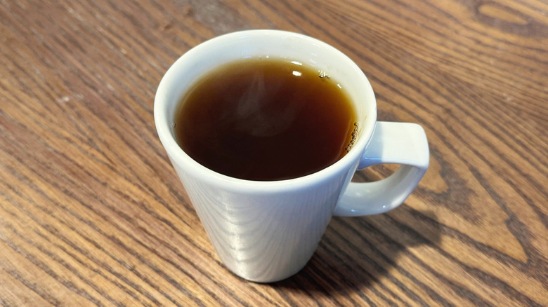 Black tea in a white mug on wooden table