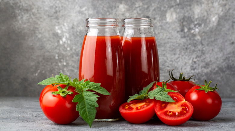 Tomato juice in glass jars with tomatoes in foreground
