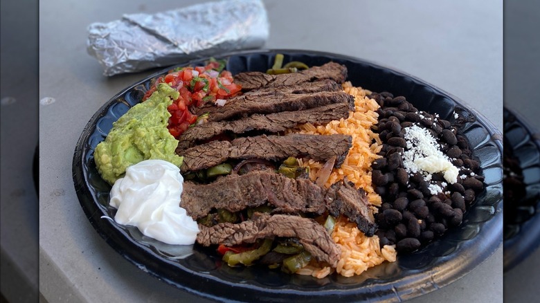 Steak fajita meat on plate with rice, beans, guac, sour cream, and pico