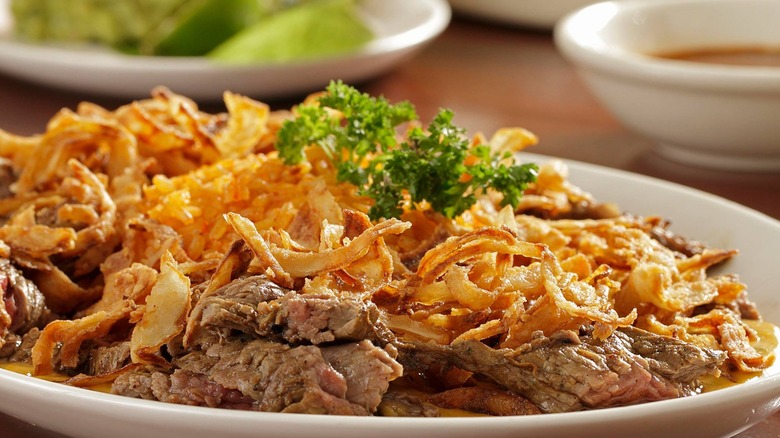 Steak fajita meat on plate with crispy fried onions