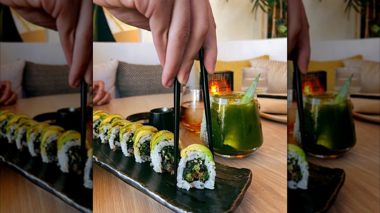hands picking up sushi with chopsticks