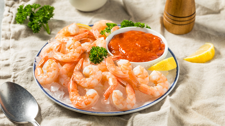 Shrimp cocktail with sauce on ice served with sauce and lemon