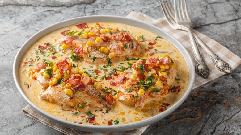 Chicken, creamed corn, and bacon with sauce on white plate.