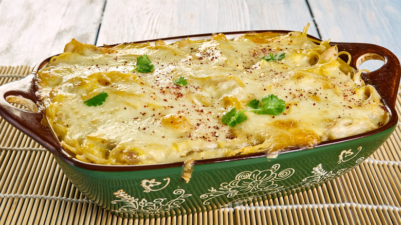 Chicken and spaghetti casserole in green decorative baking dish.