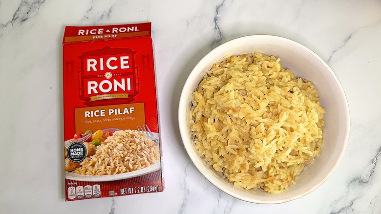 Top-down shot of bowl of Rice Pilaf Rice-A-Roni next to box on marble surface