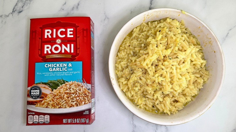 Top-down shot of bowl of Chicken & Garlic Rice-A-Roni next to box on marble surface