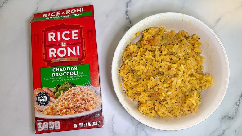 Top-down shot of bowl of Cheddar Broccoli Rice-A-Roni next to box on marble surface