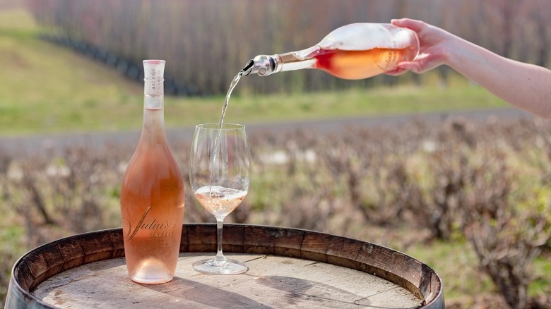 Hand pouring Long Shadows rosé wine into glass