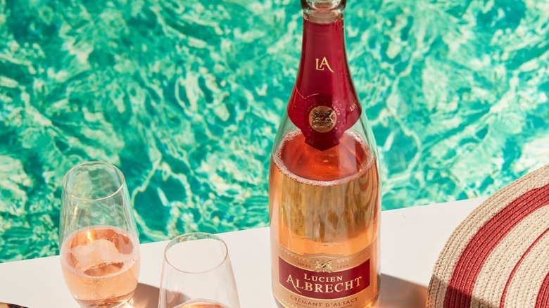 Bottle and glasses of sparkling Lucien Albrecht rosé by poolside