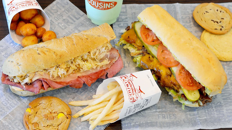 An assortment of Cousins Subs food, including cheese curds, cookies, subs, and fries