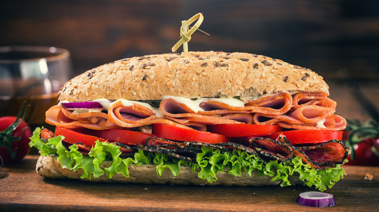 A submarine sandwich sitting on a wooden plank