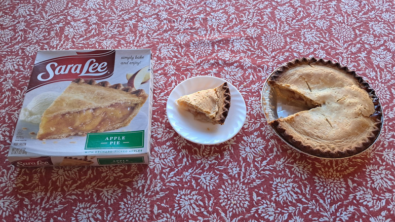 whole pie in tin next to single slice and packaging on table