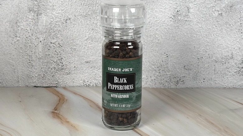 Container of Trader Joe's black peppercorns on table