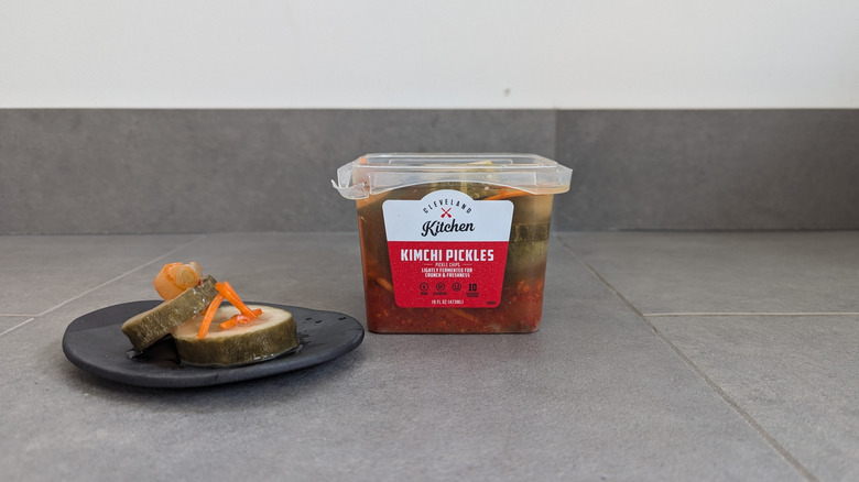 Little plastic tub of Cleveland Kitchen's kimchi-infused pickle chips next to pickle chips on a plate