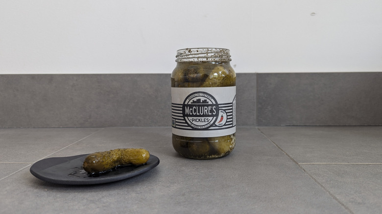 McClure's pickle jar next to a pickle on a plate
