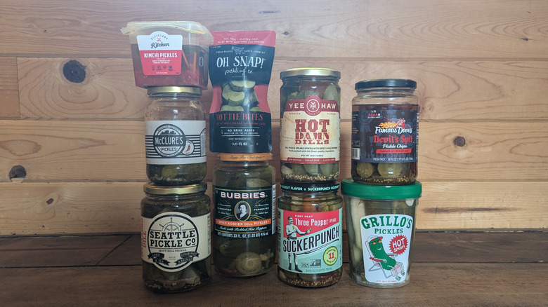 Nine different jars or pouches of spicy pickles stacked on top of each other