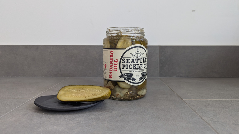 Jar of Seatle Pickle Company's halved dill pickles next to a spear on a plate