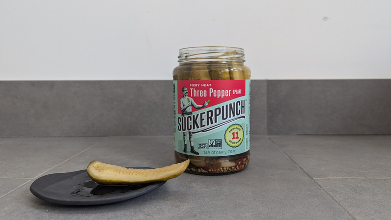 SuckerPunch pickle jar next to a pickle spear on a plate