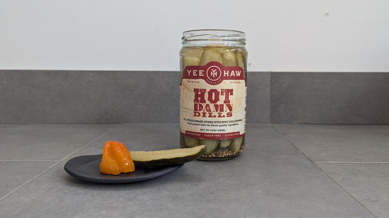 Yee-Haw pickle jar with a pickle spear and habanero pepper on a plate
