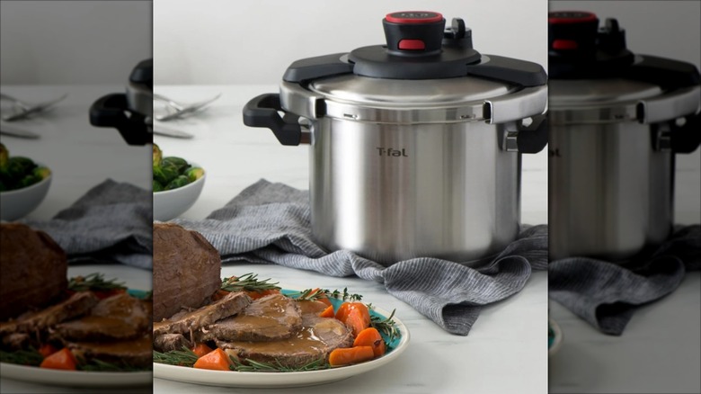 T-fal Clipso 8-quart stainless steel stovetop pressure cooker on cloth on countertop with meat dish
