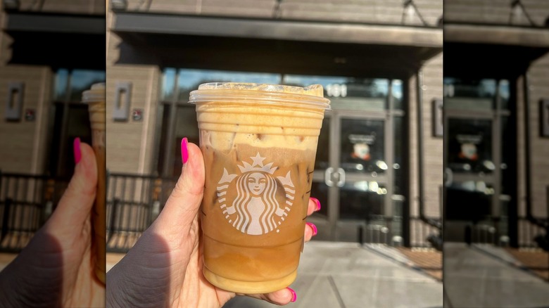 Hand holding Starbucks iced shaken espresso, topped with pumpkin cold foam