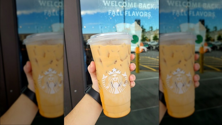 Hand holding iced pumpkin white mocha from Starbucks