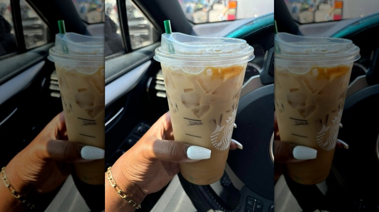 Hand holding Starbucks Pumpkin Shaken Espresso in car