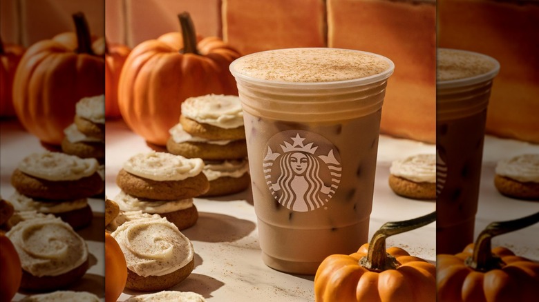 Starbucks Iced Pumpkin Cream Chai in plastic branded cup, next to pumpkins and cookies