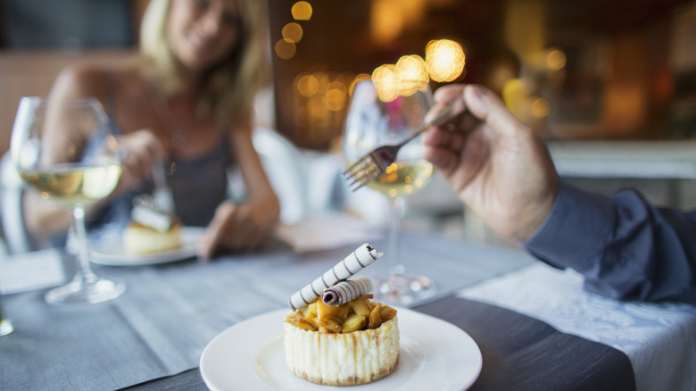 Couple at restaurant eating dessert.