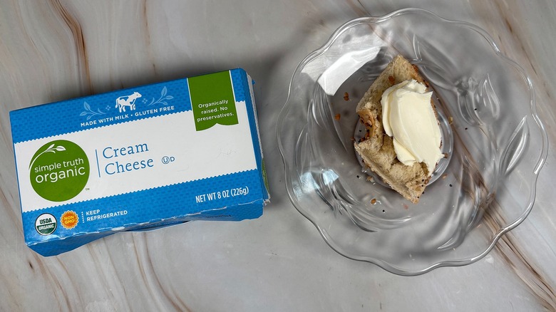 Package of Simple Truth Organic cream cheese next to bagel piece with cream cheese on glass plate