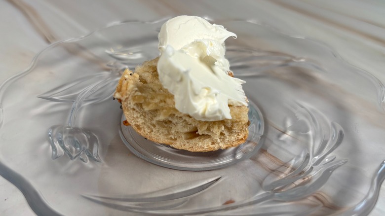 Close-up of bagel piece with cream cheese on glass plate