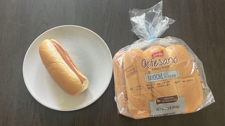 Sara Lee Artesano Brioche Style Hot Dog Buns pack with one assembled hot dog on a white plate