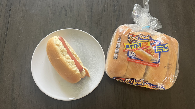 A bag of Ball Park Butter Hot Dog Buns with assembled hot dog on plate