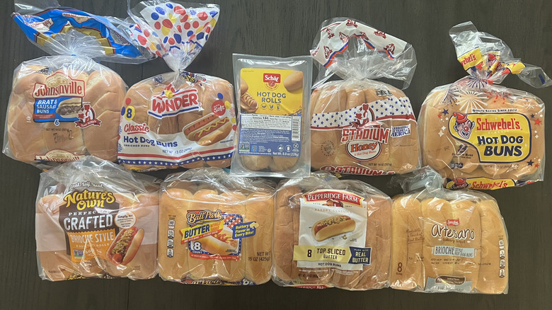 Top view of nine different brands of hot dog buns bagged and laid on a dark table