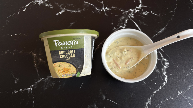 Panera broccoli cheddar soup container next to bowl of soup