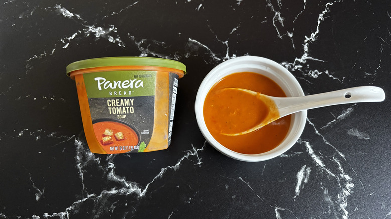 Panera creamy tomato soup container next to bowl of soup