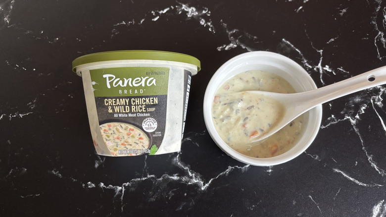 Panera creamy chicken and wild rice soup container next to bowl of soup