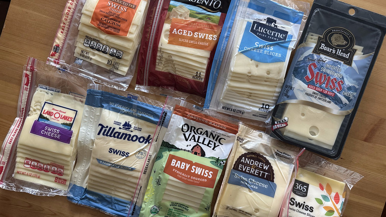 Packages of Swiss cheese on wooden table