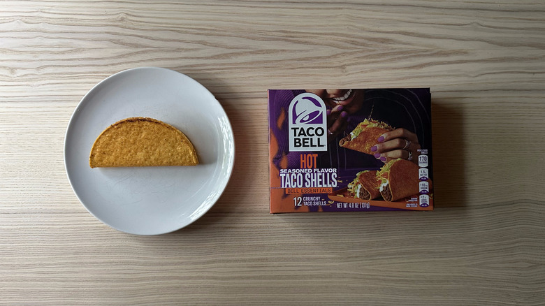 Taco Bell Hot Taco Shells box on wooden table with a plate holding one shell next to it