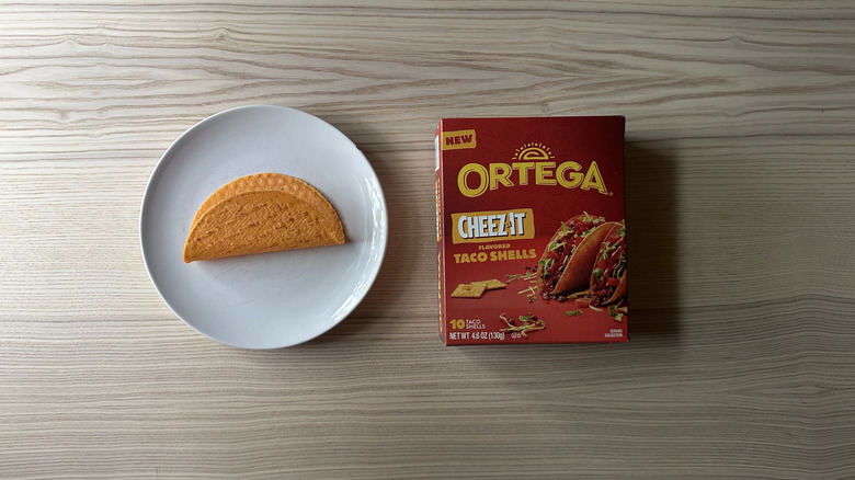 Ortega Cheez-It Flavored Taco Shells on wooden table with one shell on a plate next to the box