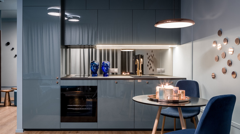 Kitchen with slate blue cabinets, metal countertop, and blue chairs