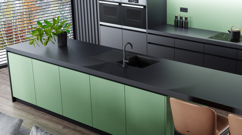Kitchen with black metal countertops and green wall and cabinets