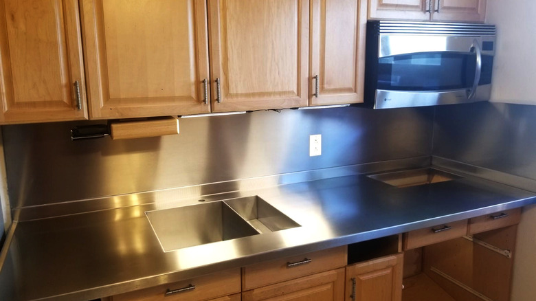 Kitchen with light wood cabinets and stainless steel counter and microwave
