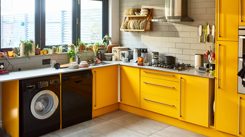 Sunny kitchen with mustard yellow cabinets and silver counters holding dishes