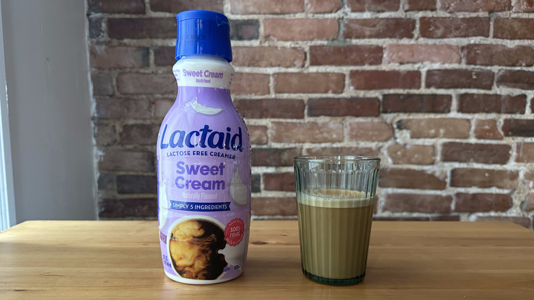 Lactaid Sweet Cream Lactose Free Creamer and cup of coffee on wooden table with brick background