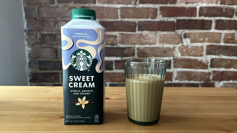 Starbucks Vanilla Inspired Sweet Cream Coffee Creamer and cup of coffee on wooden table with brick background